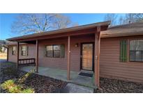 Ranch house with covered porch, brown siding, and green shutters at 557 Mccullough Rd, Stockbridge, GA 30281
