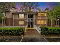 Brick condo building with a wooden walkway and lush landscaping at 261 Quail Run, Roswell, GA 30076