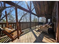Inviting covered deck with swinging chairs, outdoor seating, and natural wood finishes for relaxing in the fresh air at 49 Holly Springs Ne Rd, White, GA 30184