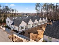 Aerial view of charming white townhouses with black roofs, lush landscaping, and tree-lined streets at 308 Chardonnay Way, Woodstock, GA 30188