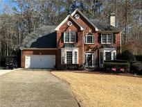 Charming two-story brick home with a well-manicured lawn, two-car garage, and mature trees at 1025 Charleston Trce, Roswell, GA 30075