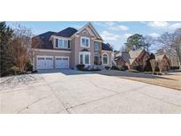 Stately two-story home with a manicured lawn, three-car garage, and a beautiful stone and stucco facade at 6705 Brookline Ct, Cumming, GA 30040