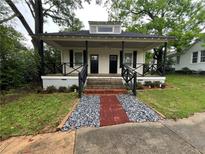 Charming home with inviting front porch, black railings, and a brick and gravel pathway to the front doors at 31 N Broad N St, Porterdale, GA 30014