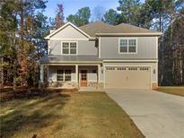 Charming two-story home with covered front porch, two-car garage, and a well-manicured lawn at 60 Hammock Dr, Covington, GA 30016