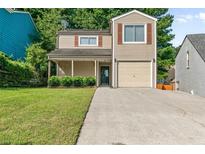 Charming two-story home featuring a well-manicured lawn, attached garage, and inviting front porch at 1184 Red Oak Cv, Tucker, GA 30084