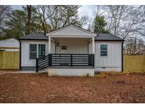 Charming renovated home featuring a covered porch and modern black railing and a well manicured lawn at 4103 Brenda Dr, Decatur, GA 30035