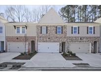 Charming townhome featuring brick and siding, complemented by individual garages and well-manicured landscaping at 691 Sunstone Ln, Lawrenceville, GA 30043