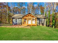 Charming gray home featuring a new front porch and lush green lawn surrounded by fall foliage at 241 Hembree Drive, Canton, GA 30115