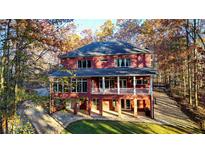 Stunning three-story red brick home with a balcony and a beautifully landscaped yard surrounded by autumn trees at 271 Brooks Rackley Rd, Dallas, GA 30157