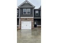Charming townhome with a white garage door and a mix of brick and gray siding at 107 Meadowview Dr # 23, Temple, GA 30179