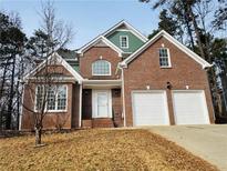 Brick two-story house with a three-car garage and landscaping at 225 Bayswater Dr, Suwanee, GA 30024