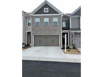 Two-story brick townhome with attached garage and landscaping at 7621 Avalon Blvd, Fairburn, GA 30213