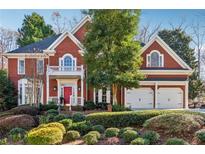 Brick house with large windows, two-car garage, and manicured landscaping at 3880 Glenhurst Se Dr, Smyrna, GA 30080