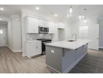 Bright kitchen features white cabinetry, gray backsplash, stainless steel appliances, and a gray kitchen island at 909 Agate Ln, Lawrenceville, GA 30043