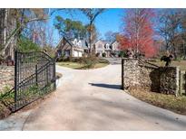 Gated driveway leading to a charming stone home with well-manicured landscaping and mature trees at 355 Clark Creek Pass, Acworth, GA 30102