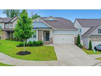 Charming home featuring stone accents, blue siding, well-manicured landscaping, and a two-car garage at 413 Solace Pl, Canton, GA 30114