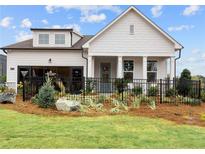 Charming single-Gathering home featuring manicured landscaping, a black fence, and a welcoming front porch at 1693 Juniper Berry Way, Loganville, GA 30052