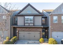 Two-story townhome with stone and siding exterior, two-car garage, and landscaping at 2354 Attewood Dr, Buford, GA 30519