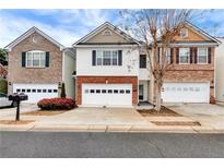 Three-unit townhome complex with attached garages and landscaping at 1967 Woodland Park Cir, Lawrenceville, GA 30043