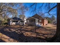 A backyard with a home, an enclosed porch, an outbuilding, and a ground covered with fallen leaves at 341 Little John Nw Dr, Lilburn, GA 30047