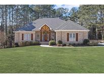 Charming brick home with a well-manicured lawn and decorative wooden accents above the front entrance at 1250 Olympic Dr, Oxford, GA 30054