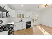 Bright kitchen featuring white cabinets, quartz countertops, black hardware, modern appliances, and french doors at 708 Martin Rd, Stone Mountain, GA 30088