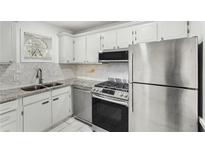 This kitchen features stainless steel appliances, white cabinets, granite countertops, and a double sink at 5400 Roswell Rd # C3, Atlanta, GA 30342
