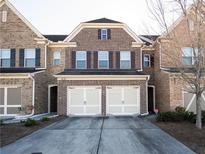 Brick front exterior of townhome with two-car garage and landscaping at 5730 Tulane Ave, Cumming, GA 30040