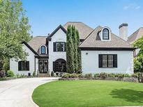 Charming two-story home with manicured lawn, arched windows, dark trim, and tasteful landscaping at 220 Windsor Gate Ne Cv, Atlanta, GA 30342