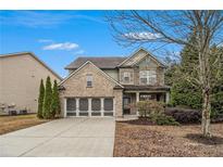 Brick two-story house with a three-car garage and landscaped yard at 881 Upland Ives Dr, Sugar Hill, GA 30518