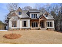 Two-story farmhouse with white siding, metal roof, and large windows at 325 Mont Harmony Sw Rd, Powder Springs, GA 30127