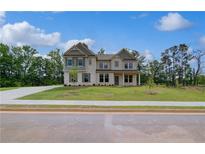 Beautiful two-story home featuring a manicured lawn and light-colored brick facade at 157 Haverling Pass, Hampton, GA 30228