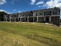 New two-story townhomes featuring brick accents, gray siding, multiple windows and a well-manicured lawn at 989 Cades Walk, Lawrenceville, GA 30045