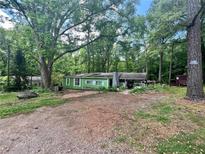 Quaint single-story home with a covered porch nestled among mature trees in a private, wooded lot at 202 Hayes St, Villa Rica, GA 30180