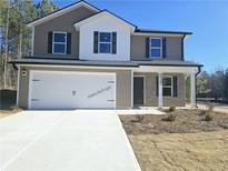 Two-story house with a white and brown exterior, two-car garage, and landscaping at 15 Barton Ln, Covington, GA 30016