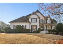 Charming two-story white brick home with a well-manicured lawn and a cozy front porch at 5975 Deerwoods Trl, Alpharetta, GA 30005