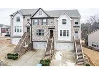 Three-unit townhome complex with attached garages and stone accents at 1957 Paxton Sw Dr, Lilburn, GA 30047