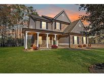 Charming two-story home with a landscaped yard, covered porch, and stone and siding accents at 324 Mary Dr, Mcdonough, GA 30252