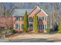 Brick two-story house with green shutters, landscaping, and a large yard at 2070 Sweetgum Trl, Cumming, GA 30041