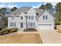 Stately two-story home featuring blue shutters, a manicured front yard, and a two-car garage at 1506 Brookridge Dr, Woodstock, GA 30189