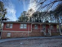 Ranch style home with brick and red siding, a covered porch and tree lined yard at 5926 Hammond Dr, Norcross, GA 30071