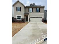 Two-story house with beige siding, a large driveway, and a two-car garage at 7709 Sudbury Cir, Covington, GA 30014