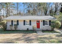 Brick ranch house with red front door, landscaping, and a spacious yard at 3212 Ward Sw Dr, Atlanta, GA 30354