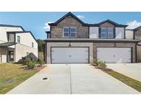 Charming two-story townhome with a brick and stone facade, attached garage, and well-manicured lawn at 273 Bald Ave, Stockbridge, GA 30253