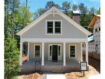 Charming exterior showcasing a covered front porch with columns, a gray facade, and a brick chimney, nestled amongst lush trees at 11792 Serenbe Ln, Chattahoochee Hills, GA 30268