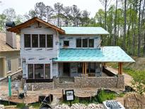 New home construction featuring a stone foundation, red-framed windows, and a partially completed roof at 11798 Serenbe Ln, Chattahoochee Hills, GA 30268