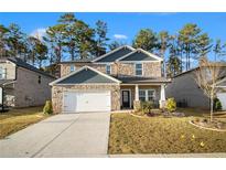 Two-story house with stone and gray siding, a two-car garage, and a landscaped yard at 7787 Richmond Trl, Fairburn, GA 30213