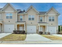 Tan 2-story townhome with 2-car garage, landscaping, and driveway at 1189 Indian Creek Pl, Stone Mountain, GA 30083