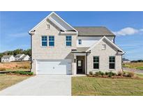 Charming two-story home with light brick, a two-car garage, and a well-manicured lawn at 726 Ocmulgee Xing, Locust Grove, GA 30248