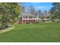 Expansive front yard featuring a two-story brick home with a welcoming, covered balcony and lush landscaping at 5651 Bahia Mar Cir, Stone Mountain, GA 30087